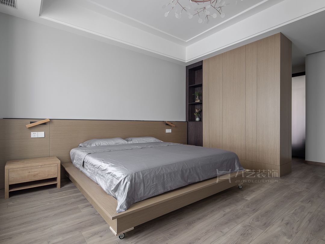 床头一角， 温润的原木半高护墙板 ， 延伸定制悬空床头柜 ，与背景纹理自然融为一体，以一副现代装饰画点缀床头背景。