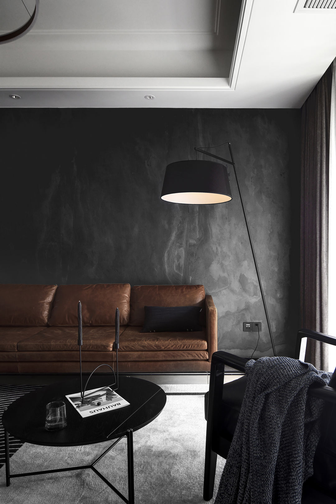 客厅的沙发背景墙铺上了一款黑色的岩板,纹理丰富多变,优雅大气,每片